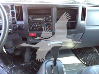 Truck cab interior showing dashboard controls, center stack with radio, climate controls, gear shifter, and empty passenger display window.
