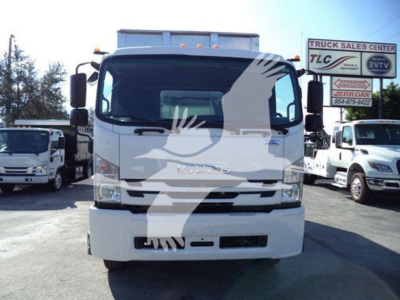 Isuzu cab of a 2018 FTR truck showing front grille, windshield, headlights, and side mirrors; signage in background includes TLC Truck Sales Center