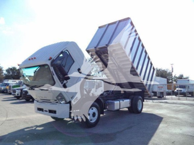 Isuzu FTR truck with tilted dump bed, front cab shows steering wheel and dash; no legible labels visible