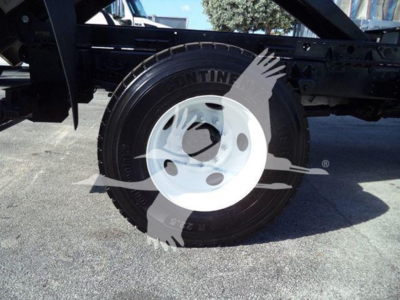 Isuzu FTR wheel and tire mounted on chassis, white steel wheel with black tire, exposed frame and undercarriage components visible.