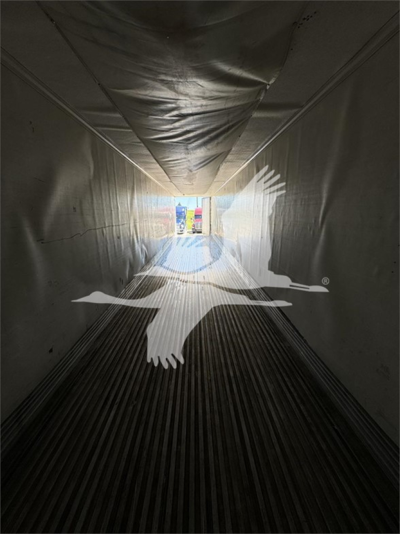 Interior of a 2011 Wabash reefer trailer showing insulated walls and ribbed floor with light at the far end. Overlay graphic of a bird in flight appears across the center.