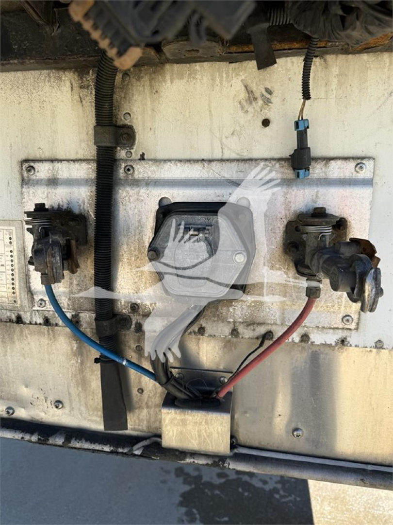 Trailer electrical connection panel on a Wabash reefer trailer showing two circular connectors, blue and red power lines, black wire harness, and a central rectangular filter or plug.