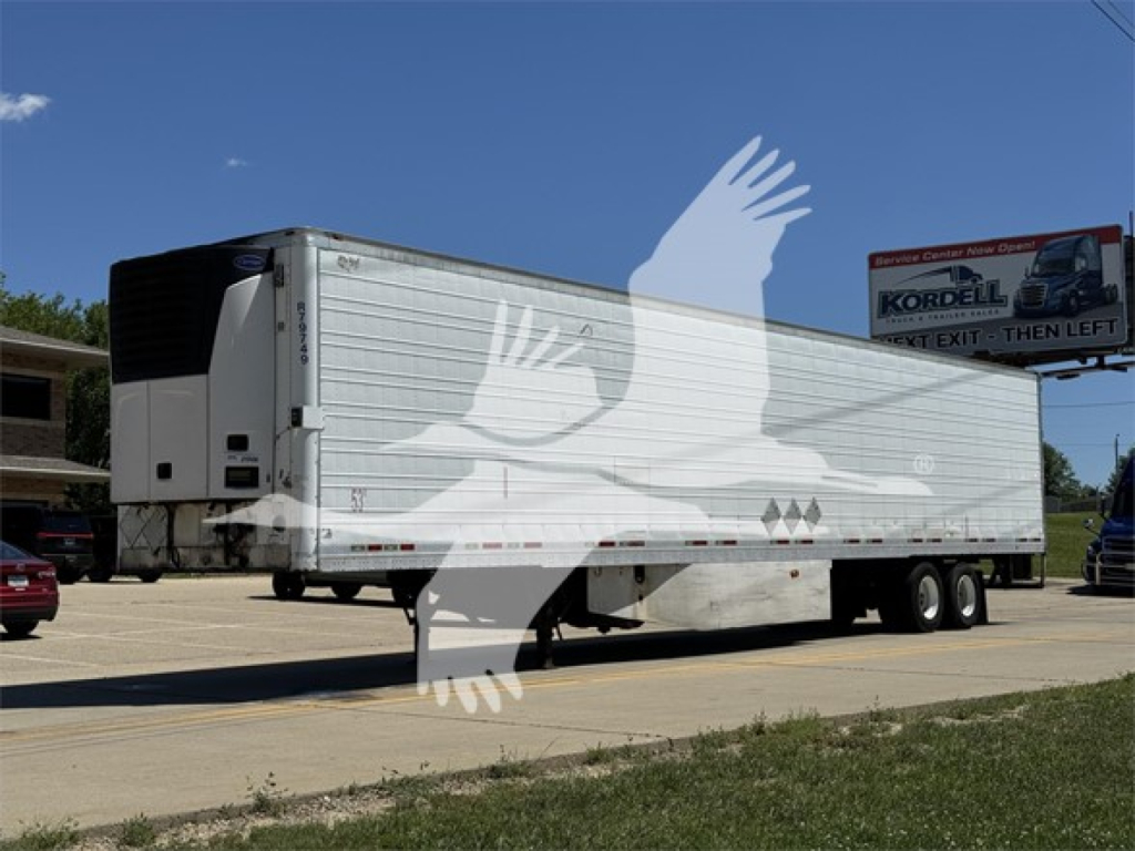 Wabash reefer trailer with silver sides and dual rear axles, side text visible, parked on road.