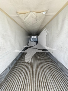 Trailer interior showing ribbed floor and walls of a reefer with natural light at far end