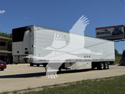 Wabash reefer trailer with silver sides and dual rear axles, side text visible, parked on road.