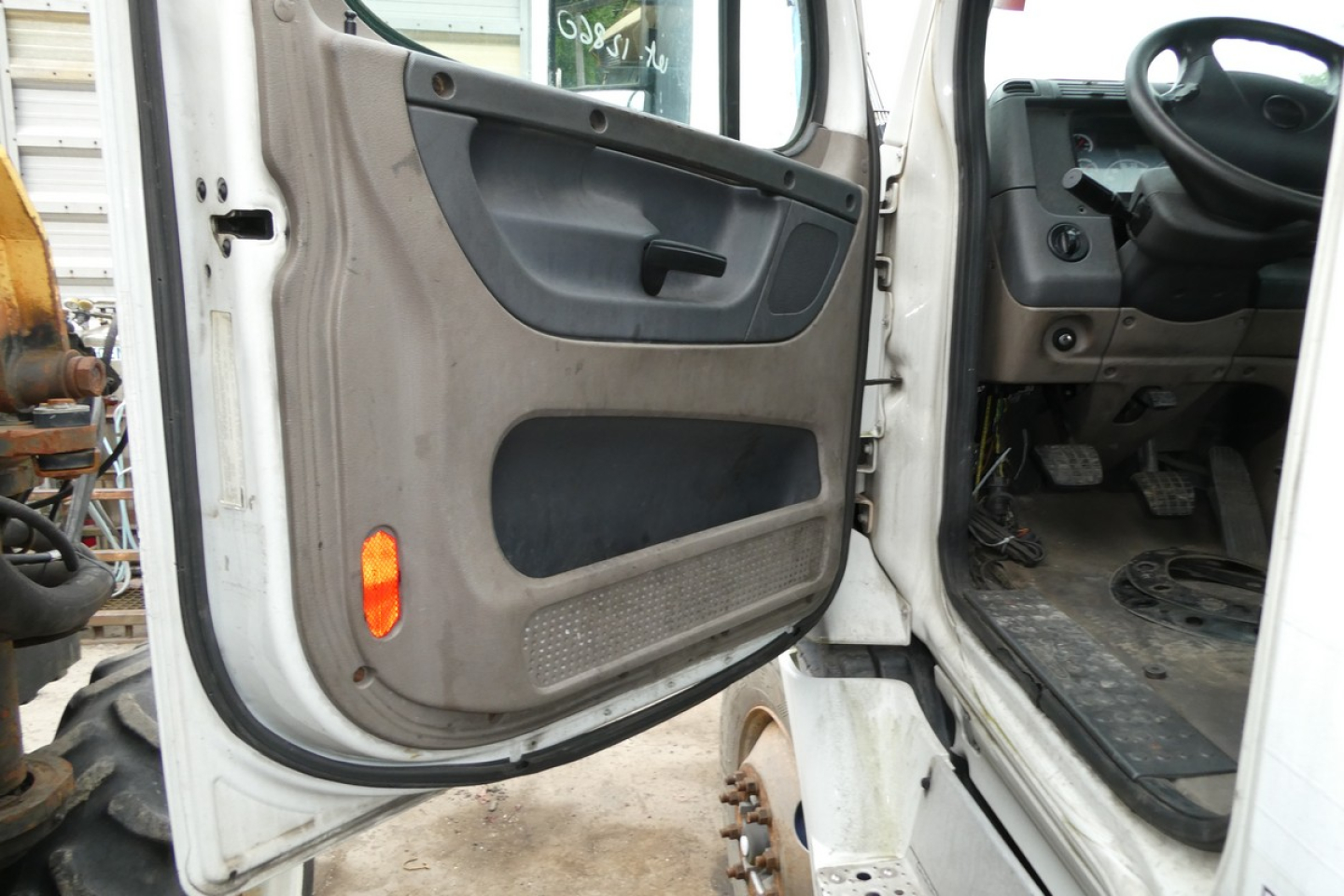 Truck cab interior door view showing passenger side door panel and part of dashboard in Freightliner Cascadia 113 exterior; steps and pedals visible.