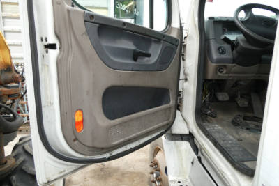 Truck cab interior door view showing passenger side door panel and part of dashboard in Freightliner Cascadia 113 exterior; steps and pedals visible.