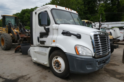 Freightliner Cascadia 113 semi truck cab in yard with white exterior and black front bumper, stock tires, side mirrors, and visible cab steps.
