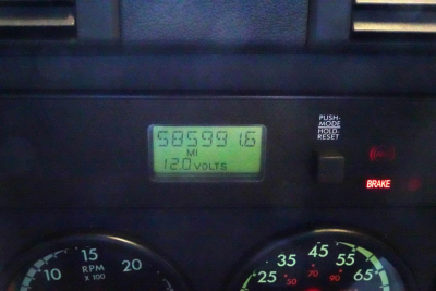 Dashboard view showing digital odometer reading 585,959.6 miles and 12.0 volts, with brake indicator and RPM/MPH gauges visible.