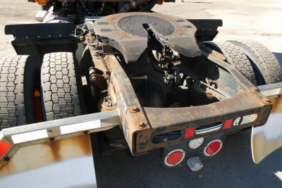 Tractor-trailer fifth wheel and rear chassis of a 2012 Freightliner Cascadia 125 showing rusty frame and mud-spattered wheels.