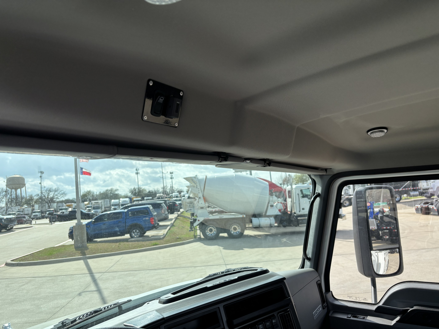 Dashboard and windshield view of a new 2025 Mack MD7 truck cab interior with side mirror visible.