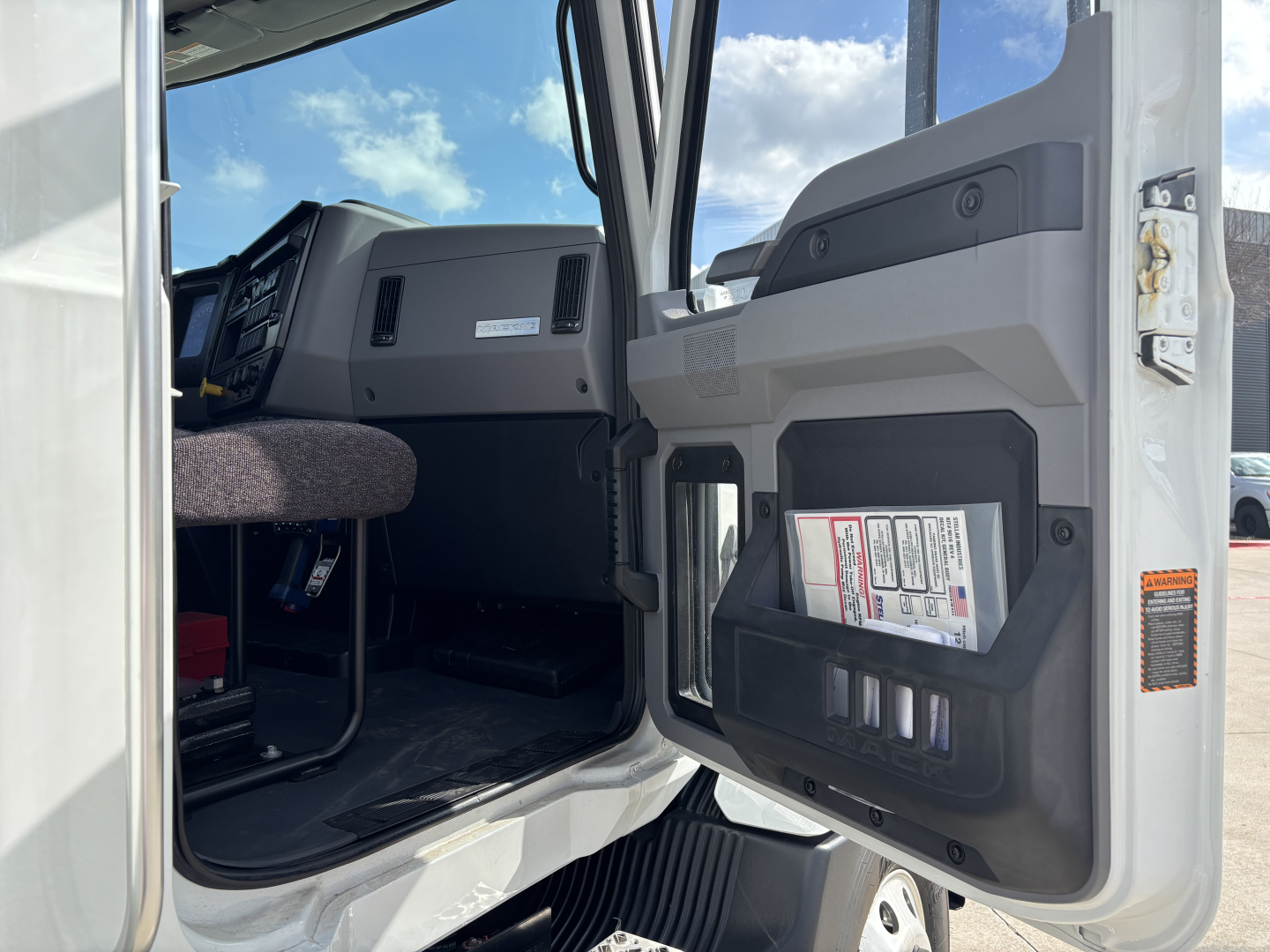 MD7 truck cab interior door panel with pockets and labels visible, front seat and dashboard area seen from open driver door.