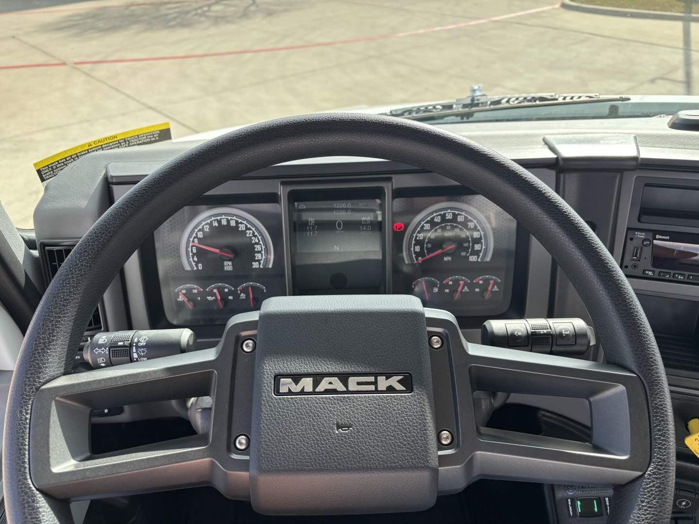 Mack MD7 truck cockpit showing steering wheel with MACK branding and instrument cluster.
