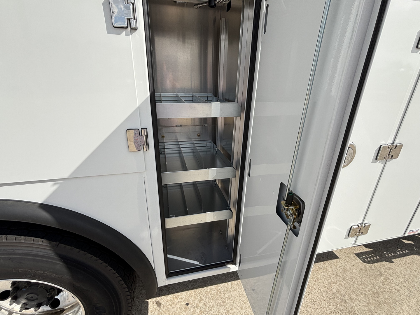 Service/Utility truck compartment with open cabinet showing metal shelves inside.