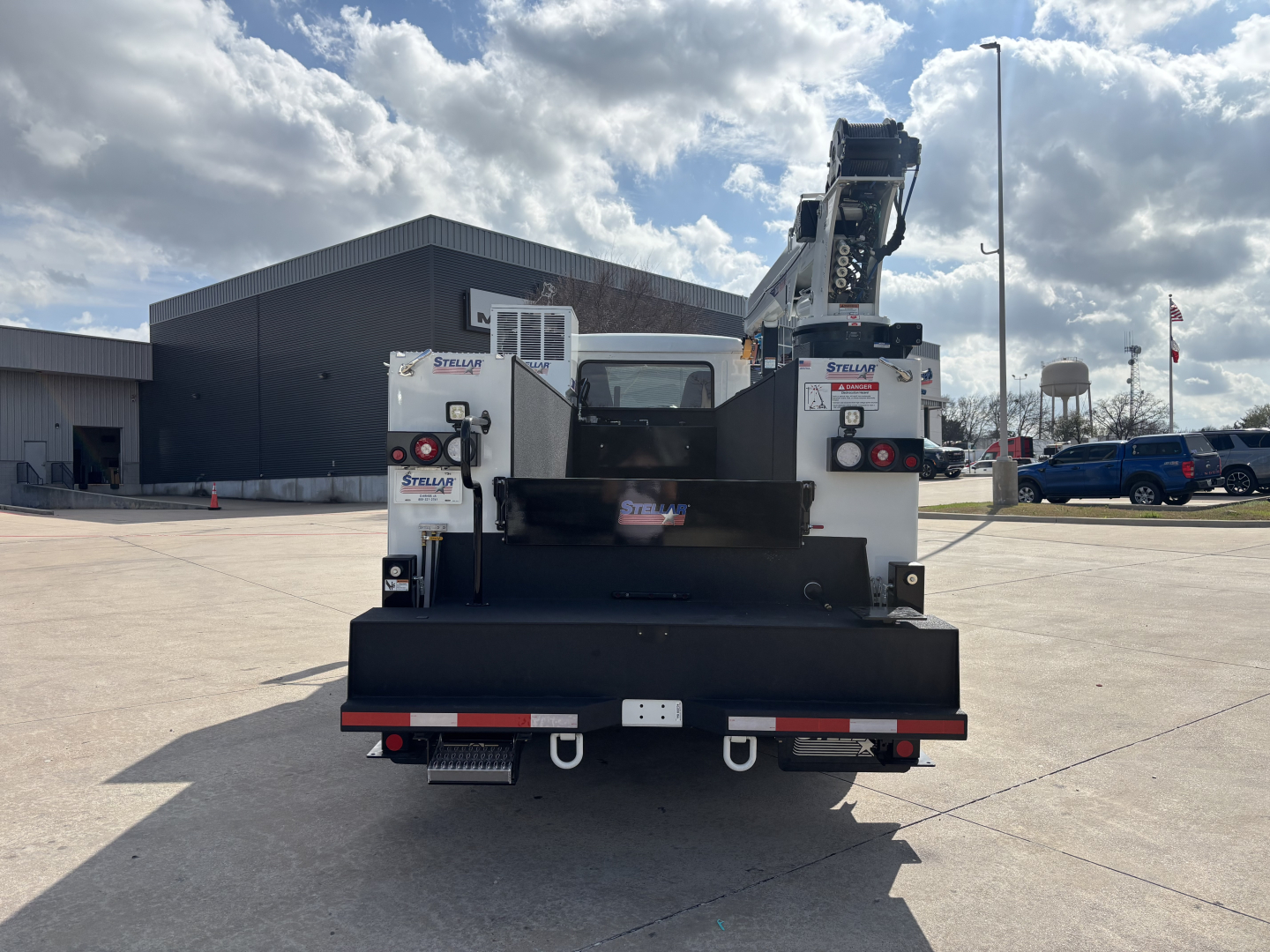 Mack MD7 service truck rear view showing crane and flatbed with safety reflectors and lights.