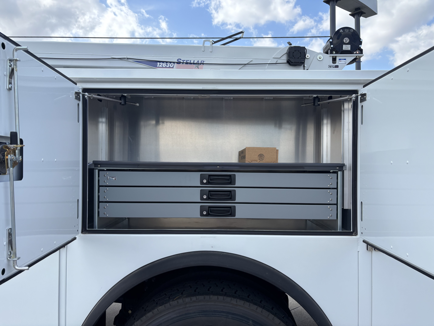 MD7 service truck rear storage drawers open showing three slide drawers and stainless interior; some cardboard box on top shelf.