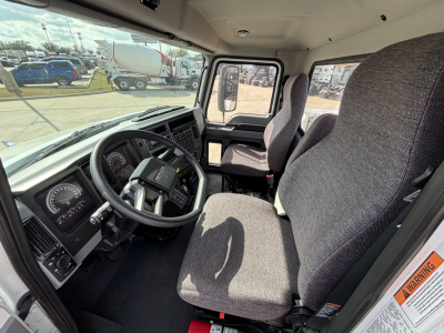 Interior of a new 2025 Mack MD7 truck cab showing steering wheel, dashboard, driver seat, and passenger seat in view.