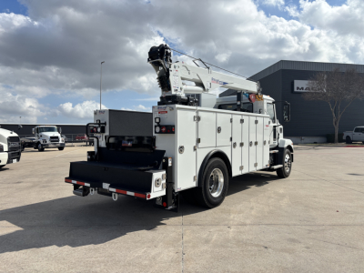 Service body truck with crane on site showing white utility truck with compartments and crane at rear.