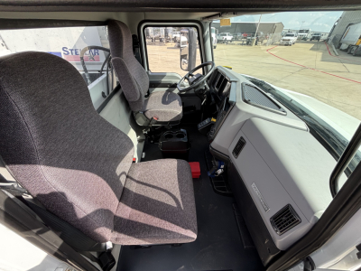 Driver cockpit of a 2025 Mack MD7 service/utility truck showing the steering wheel, dashboard with vents, and two front seats.