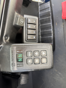 Mack MD7 cab interior showing control panel with gear buttons and auxiliary switch cluster including blinkers and window controls.