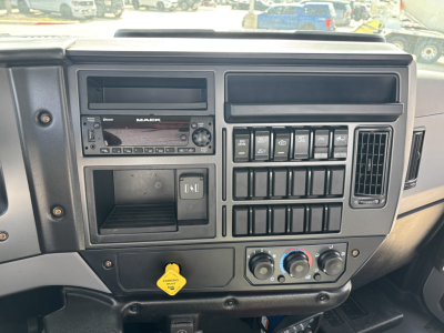 Mack MD7 dashboard and center console showing radio, multiple toggle switches, climate controls, and a yellow ignition key attached.