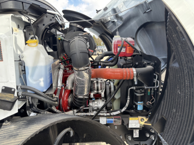 MD7 engine bay showing coolant reservoir, air intake hose, red exhaust/intercooler piping, battery, and various hoses and clamps.