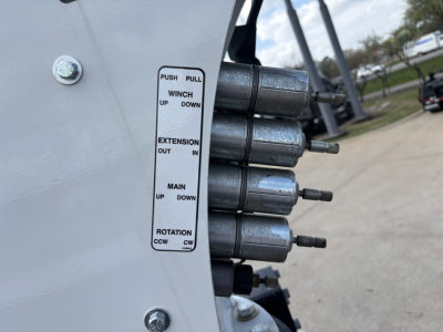 Panel with labeled switches showing PUSH PULL, WINCH UP DOWN, EXTENSION OUT IN, MAIN UP DOWN, ROTATION CCW CW with three cylindrical pins adjacent.