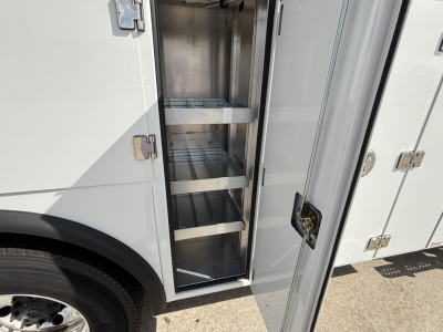 Service/Utility truck compartment with open cabinet showing metal shelves inside.