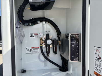 Panel inside a Mack MD7 service/utility truck showing gauges, hoses, and control switches. Visible text includes warning labels and a vertical panel with buttons