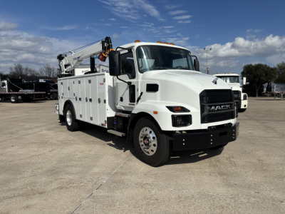 Mack MD7 service truck in white with utility compartments and crane, side view showing front grille with MACK logo and crane arm folded on top.