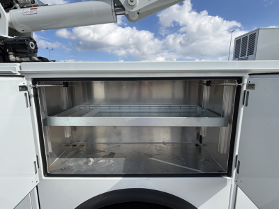 Mack MD7 service truck with open storage compartment showing metal shelves and interior walls.