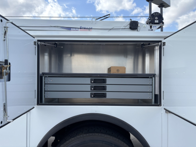 MD7 service truck rear storage drawers open showing three slide drawers and stainless interior; some cardboard box on top shelf.