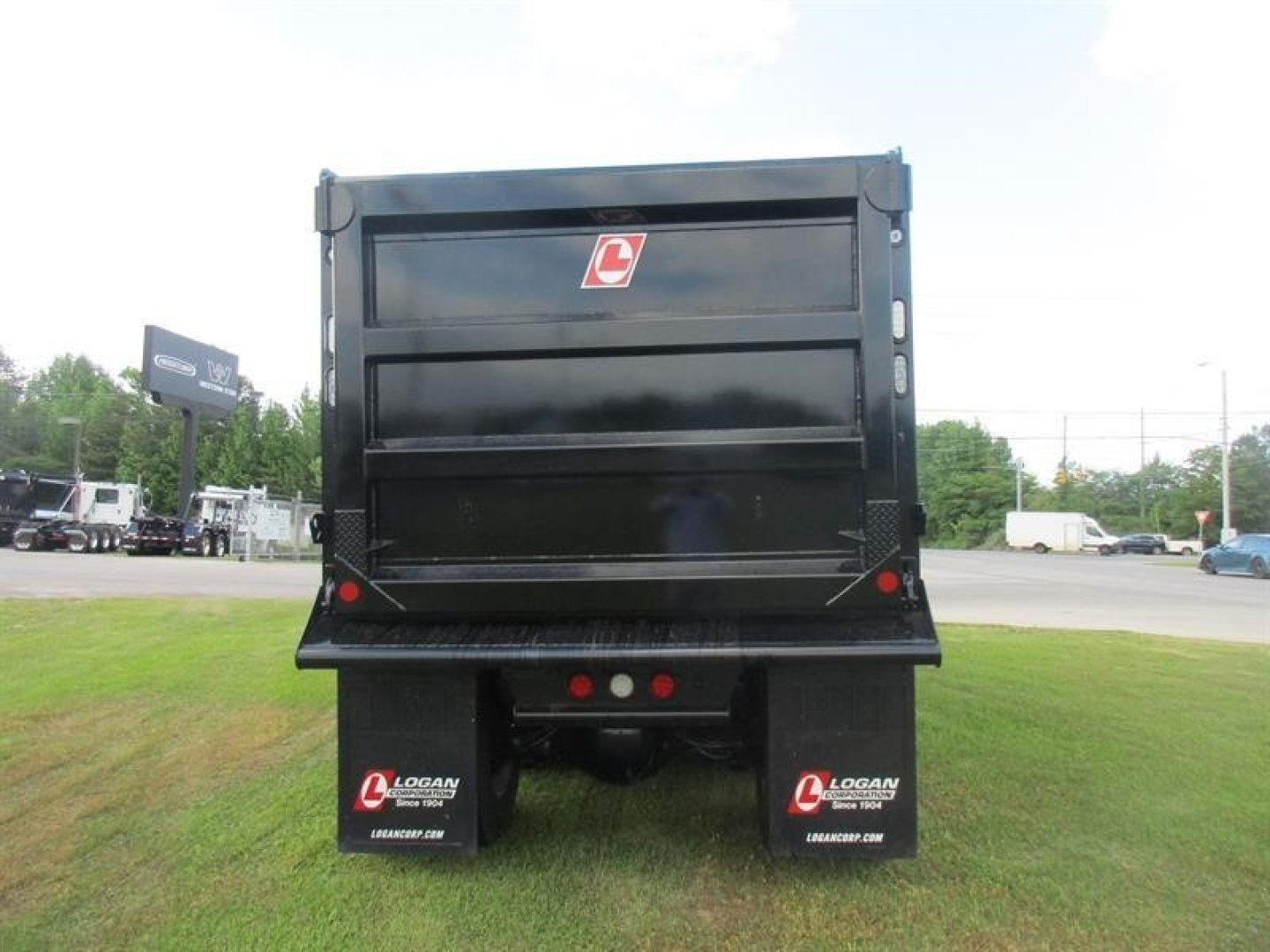 Dump truck rear view showing cargo bed and rear Mud flaps with logo, tail lights, and bumper on a Western Star 49X chassis.
