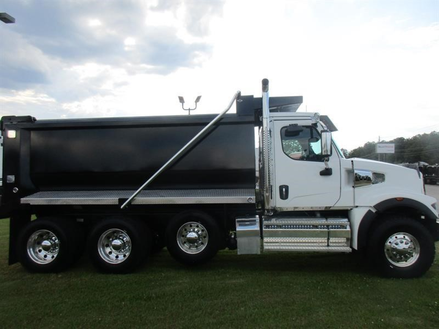 Western Star 49X dump truck in side profile showing black dump body, white cab, dual rear axles, chrome fuel tanks, and wheel rims.