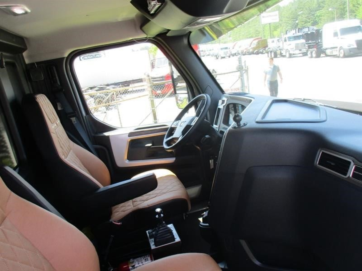 Interior of a new Western Star 49X dump truck cab showing driver seat, steering wheel, and dashboard with tan quilted seats.