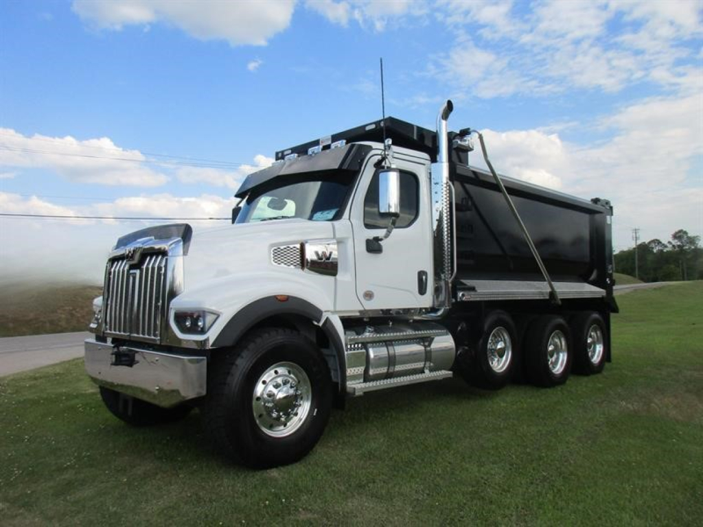 Western Star 49X dump truck with white cab and black dump bed, 6-wheel drive, on grass under blue sky.