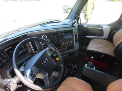 Dashboard and steering wheel of 2026 Western Star 49X truck interior showing steering wheel, infotainment screen, and tan seat.