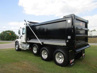Truck dump bed on a new Western Star 49X with a triple-axle rear, black dump body, chrome wheels, and cab visible in side view.