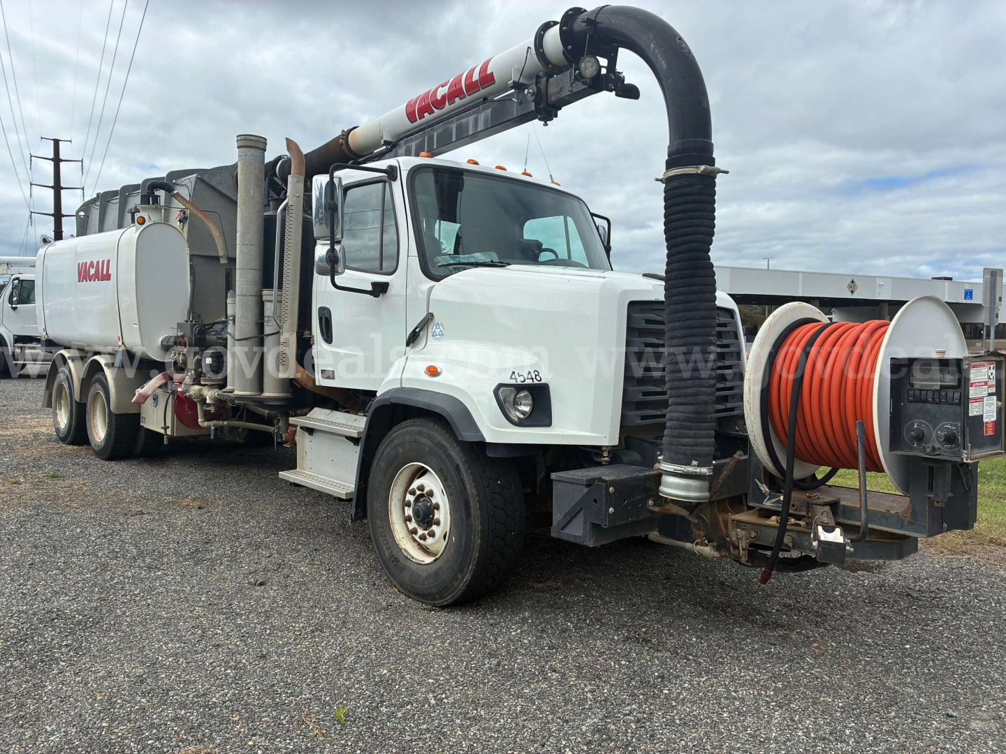 Freightliner 108SD vacuum truck showing hose reel and vacuum system with KCALL branding on upper boom and rear tank unit.