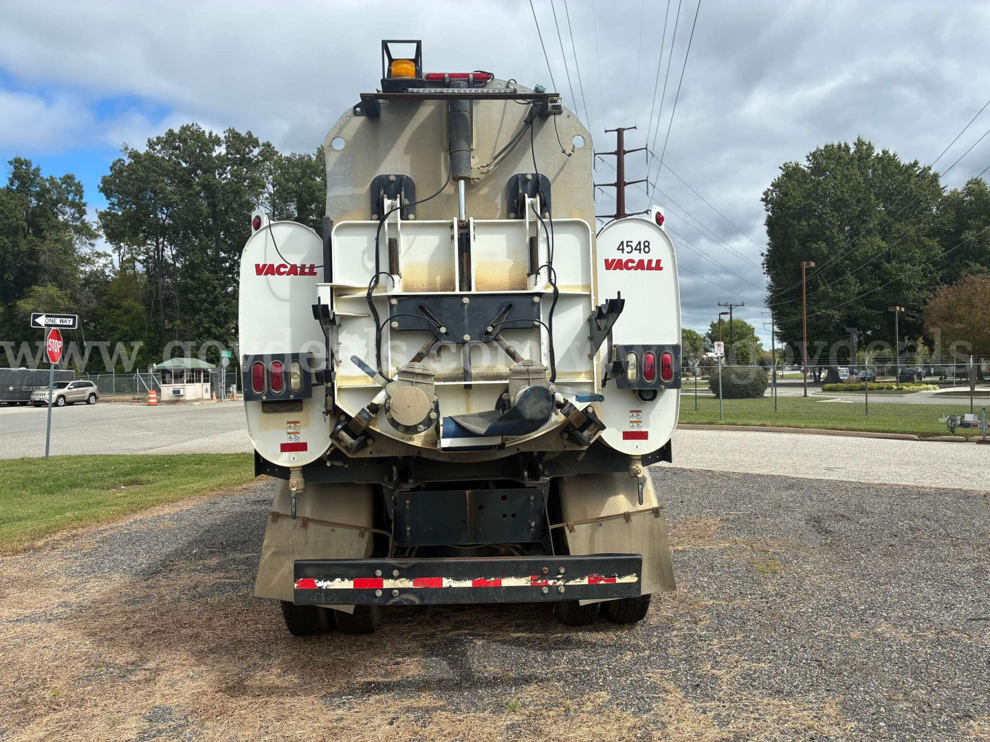 Back view of a Freightliner 108SD vacuum truck showing rear platform, hose reels labeled VACALL, and taillights.