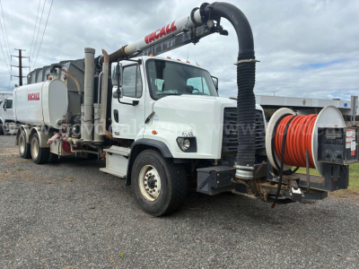 Freightliner 108SD vacuum truck showing hose reel and vacuum system with KCALL branding on upper boom and rear tank unit.