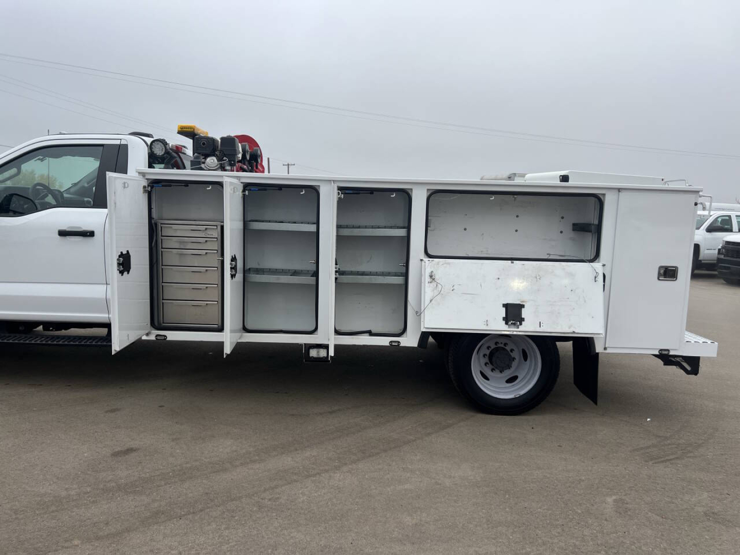 Side view of a Ford F550 service utility truck with open compartments and tool storage bays.