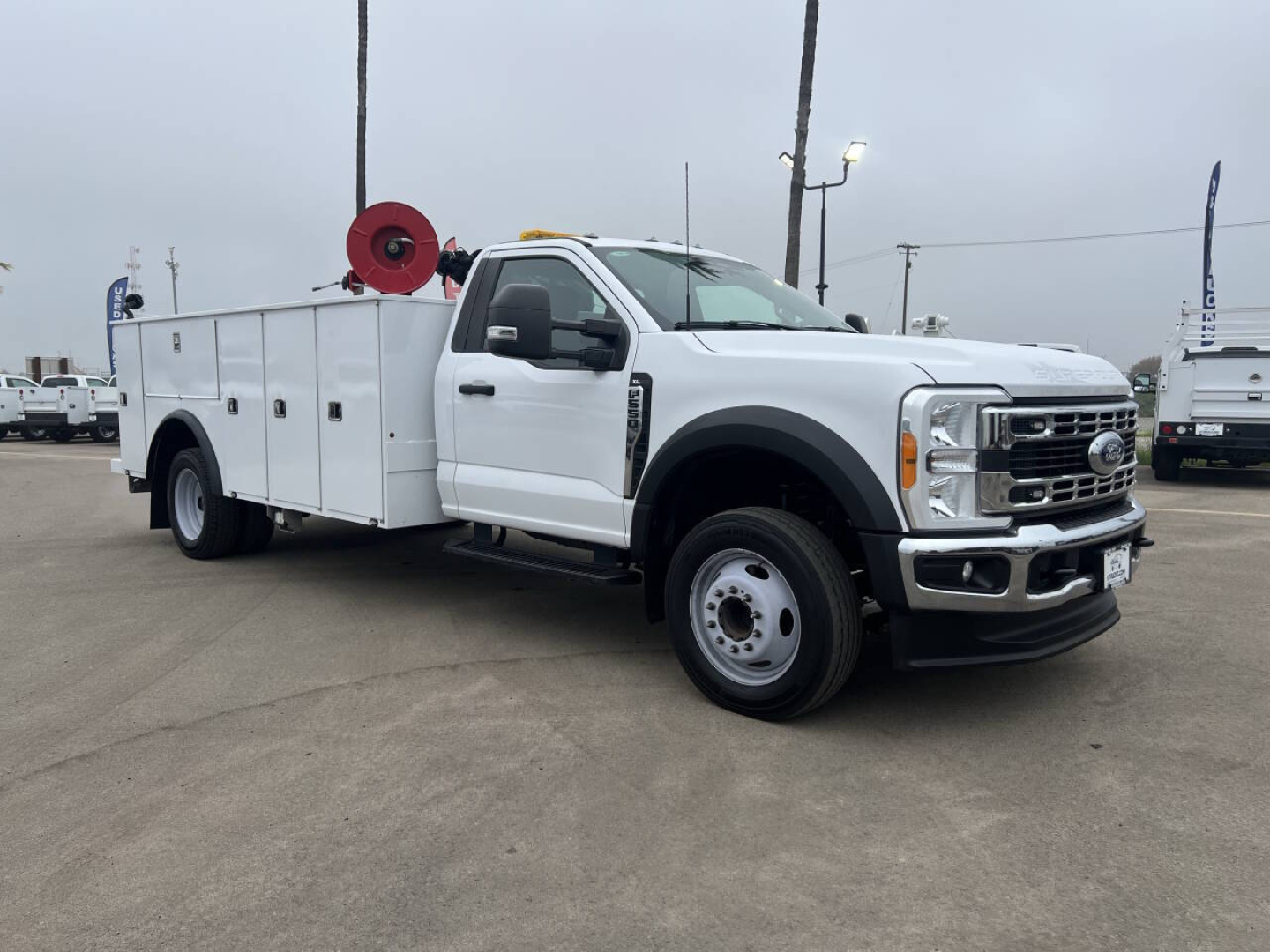 Service/utility truck showing white Ford F-550 with utility bed and mounted reel, side view, stock number 7731.