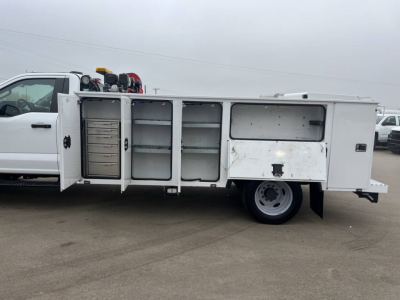 Side view of a Ford F550 service utility truck with open compartments and tool storage bays.