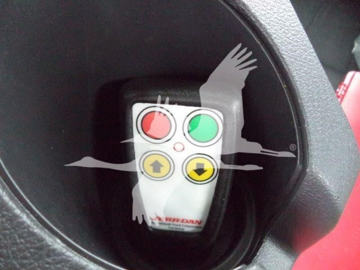 Control switch with red, green, up, and down buttons inside a circular console on a Freightliner M2 106 rollback truck.