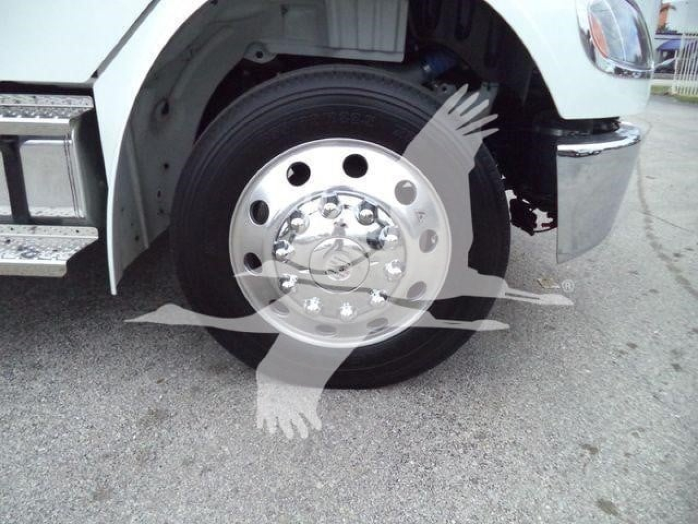 Truck wheel with polished steel hub and black tire, front fender and chrome bumper visible.