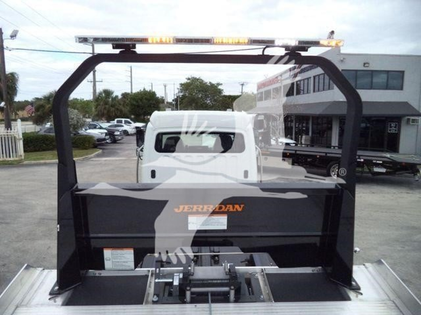 Truck bed with hydraulic system and roll-back platform inside Freightliner M2 106 service area showing 'JERR-DAN' branding on platform.