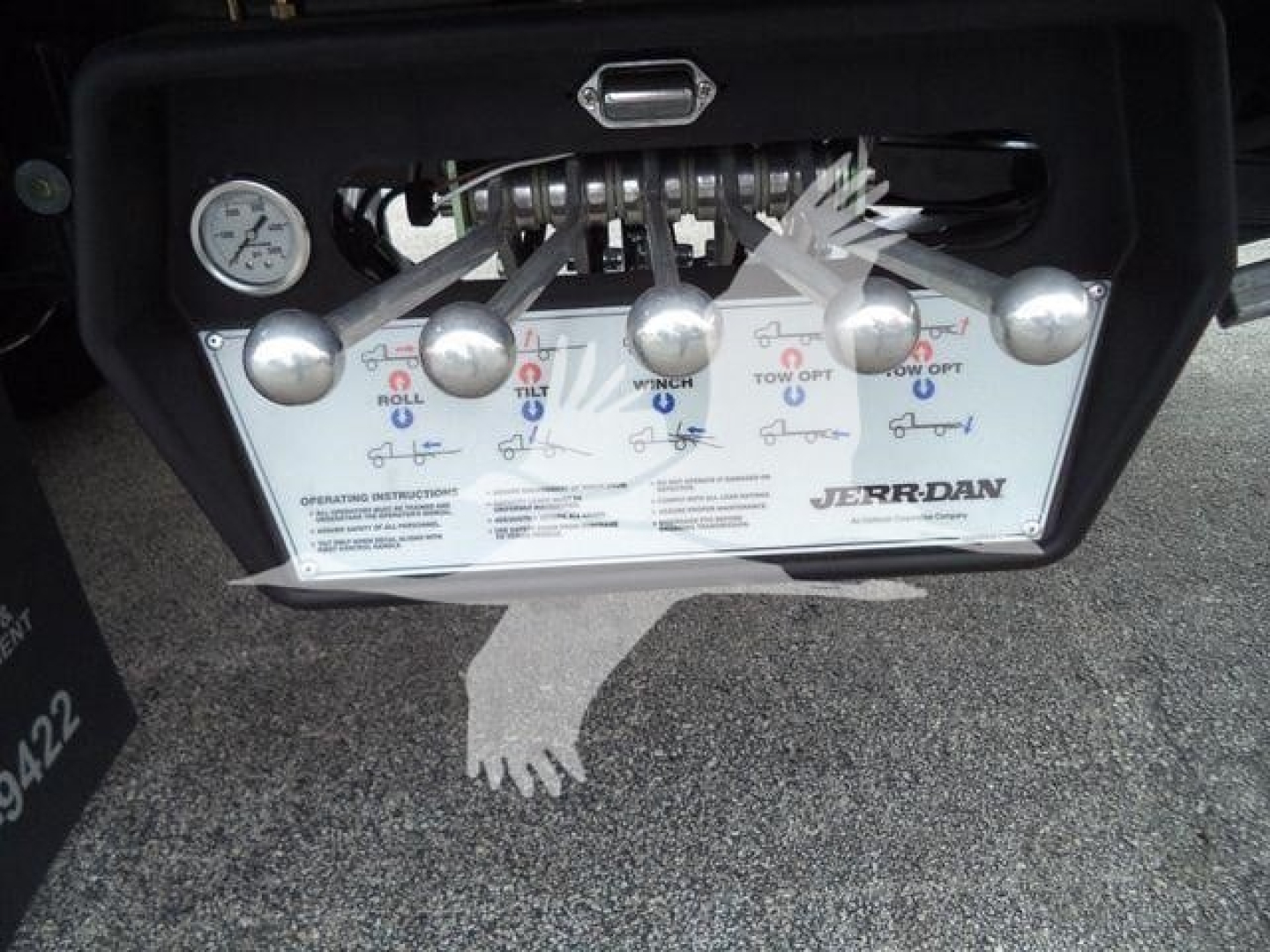 Panel with six control levers labeled ROLL, TILT, WINCH, TOW, HEIGHT? and others; gauge visible; JERR-DAN branding on lower right; operating instructions text; metal hoses above levers.