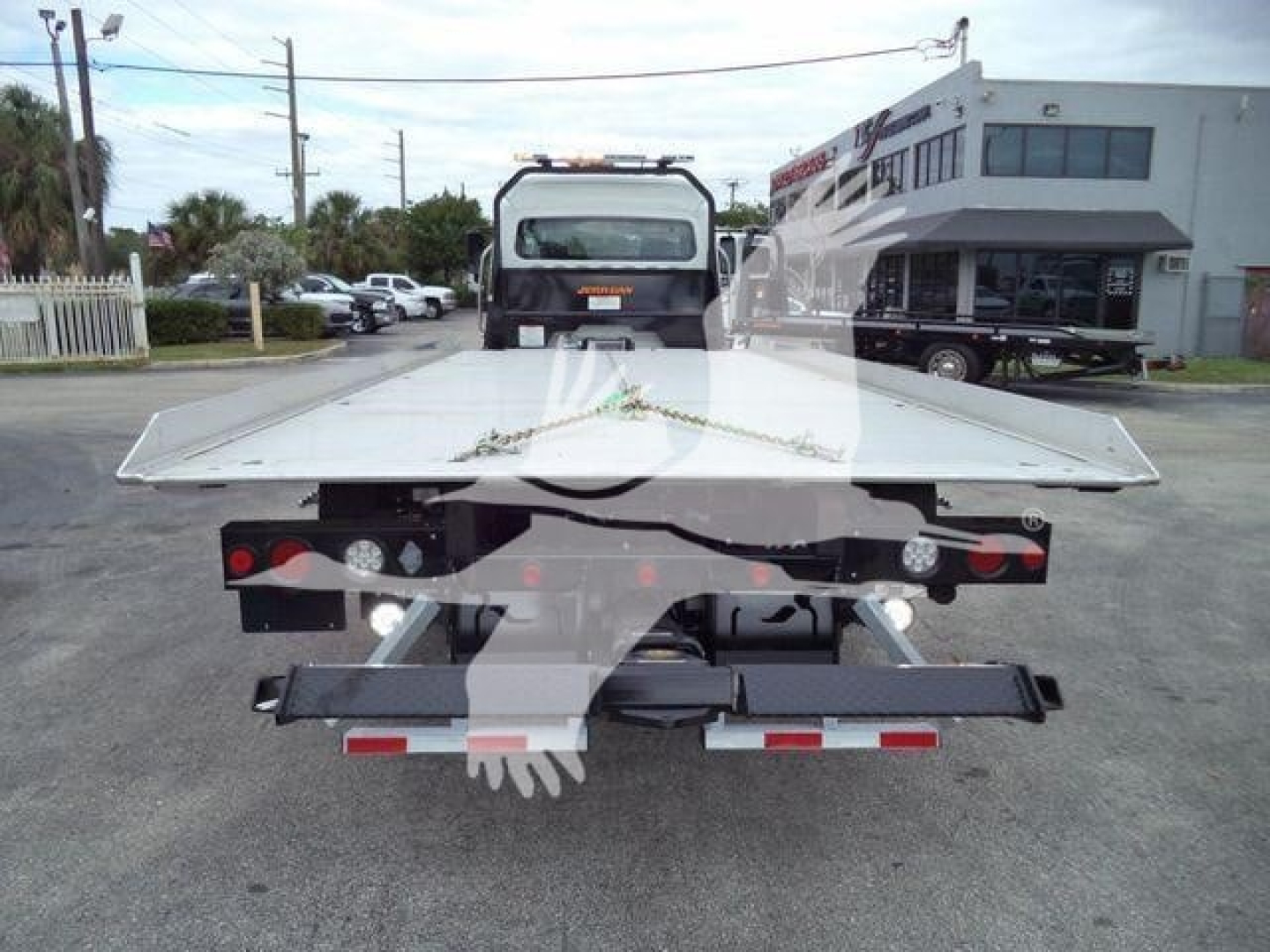 Freightliner M2 106 rollback bed back view showing flatbed platform and light bar on cab, in-service.