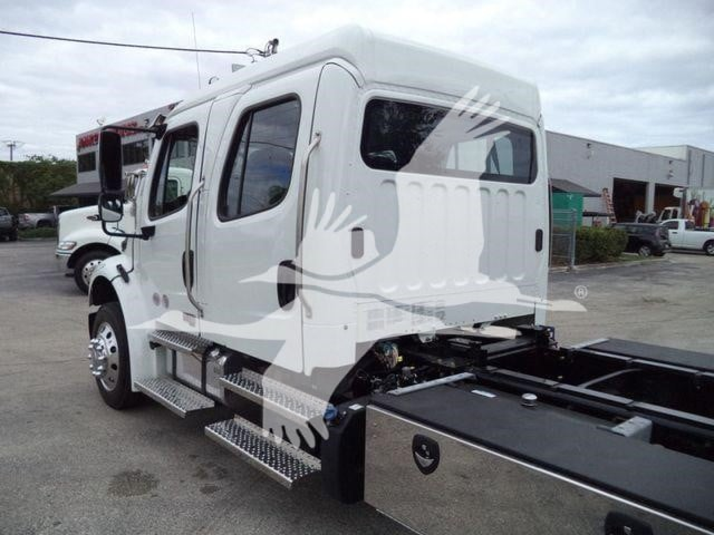 Freightliner M2 106 rollback truck cab rear view showing side steps and chassis bed.